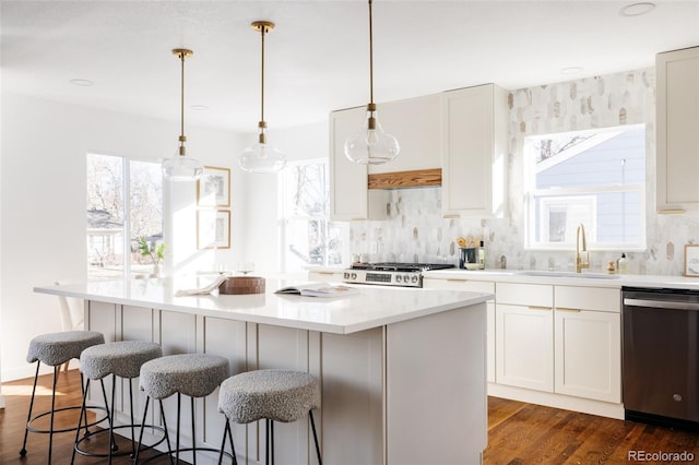 kitchen with sink, range, a center island, hanging light fixtures, and stainless steel dishwasher