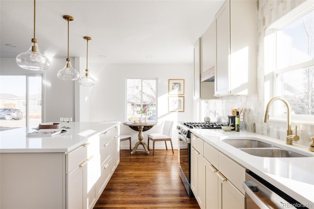 kitchen with appliances with stainless steel finishes, sink, white cabinets, backsplash, and hanging light fixtures