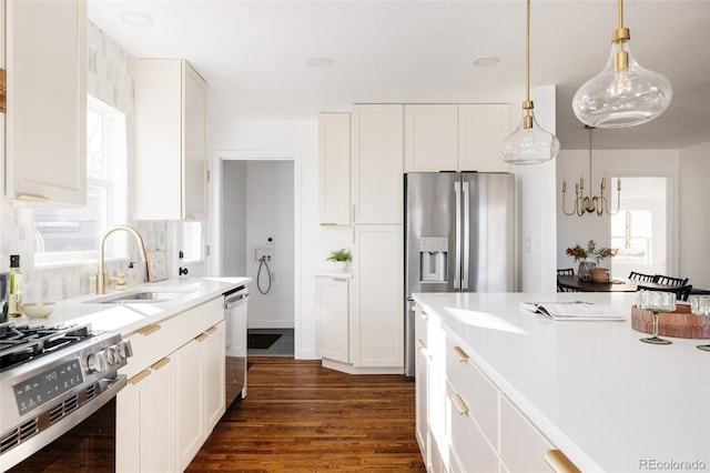 kitchen featuring white cabinetry, stainless steel appliances, decorative light fixtures, and sink