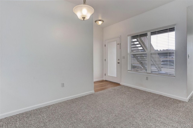 spare room featuring light colored carpet and baseboards