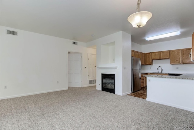 kitchen featuring brown cabinets, light countertops, visible vents, freestanding refrigerator, and open floor plan