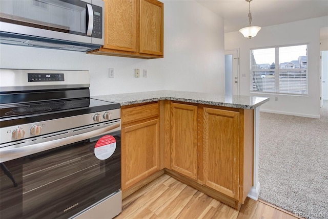 kitchen featuring light stone counters, brown cabinets, a peninsula, stainless steel appliances, and light wood-type flooring