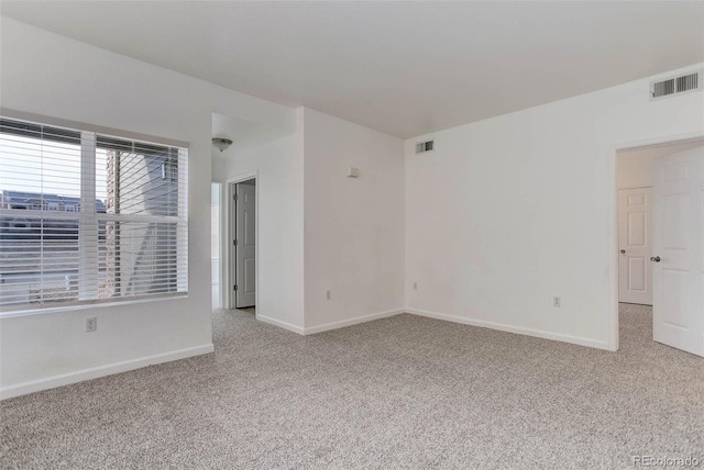 empty room with light colored carpet, visible vents, and baseboards