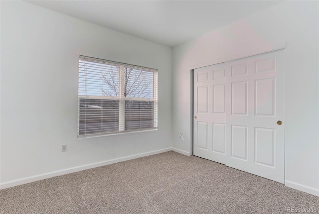 unfurnished bedroom with carpet floors, a closet, and baseboards