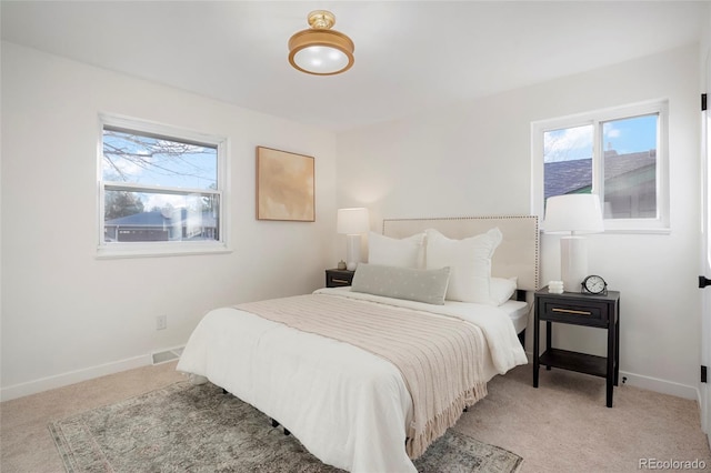 bedroom featuring multiple windows, light carpet, and baseboards