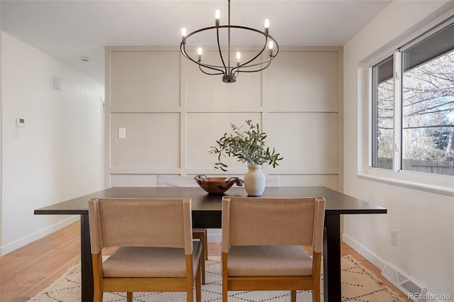 dining space with visible vents, light wood-style flooring, baseboards, and an inviting chandelier