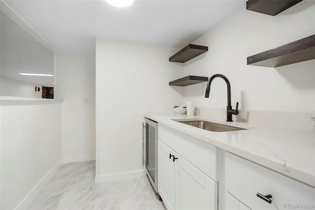 kitchen with white cabinets, marble finish floor, light stone countertops, open shelves, and a sink