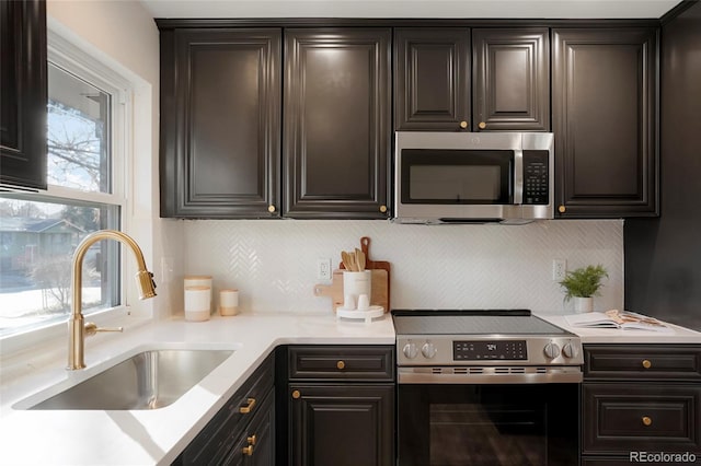 kitchen with stainless steel appliances, light countertops, a sink, and backsplash