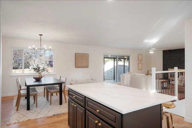 kitchen with a center island, decorative light fixtures, light wood finished floors, light countertops, and open floor plan