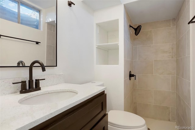 bathroom featuring tiled shower, vanity, and toilet