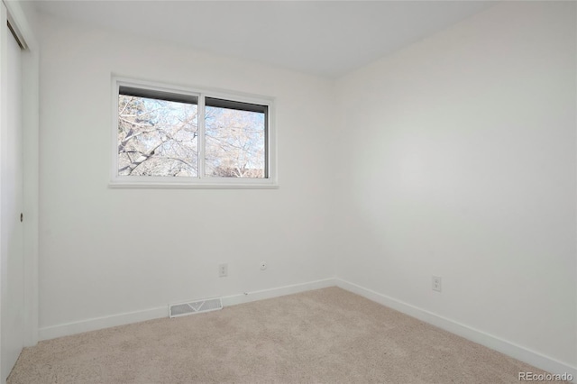 carpeted spare room with visible vents and baseboards