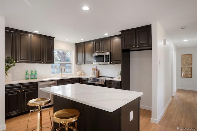 kitchen with light wood-style flooring, a kitchen island, stainless steel appliances, and a sink