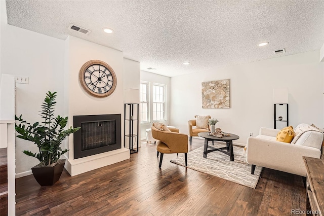 13020 E Linvale Pl, Aurora, CO 80014 - living area with a textured ceiling, visible vents, a fireplace with raised hearth, and hardwood / wood-style flooring