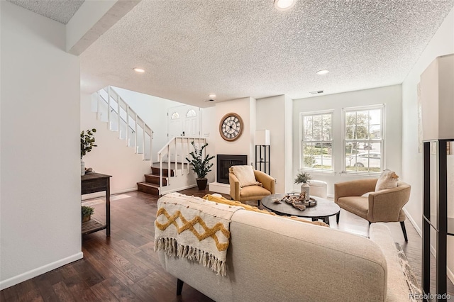 13020 E Linvale Pl, Aurora, CO 80014 - living area featuring stairs, a textured ceiling, visible vents, a fireplace with raised hearth, and dark wood finished floors