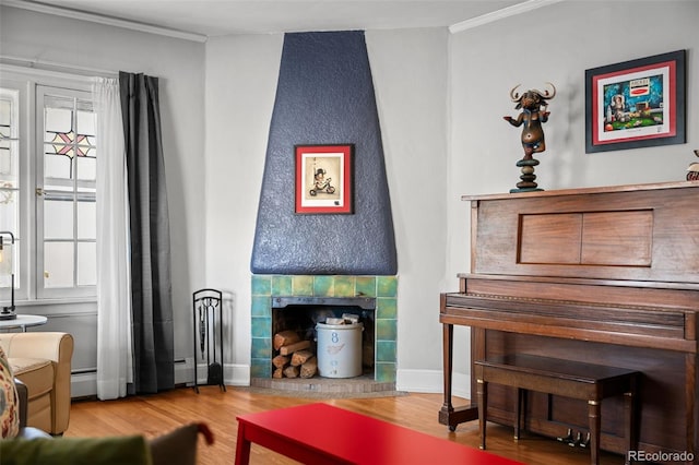 living area featuring a tile fireplace, wood finished floors, baseboards, ornamental molding, and baseboard heating