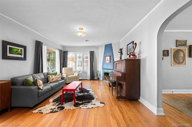 living room with arched walkways, light wood-style flooring, baseboards, baseboard heating, and crown molding