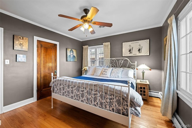 bedroom featuring a baseboard heating unit, baseboards, crown molding, and light wood finished floors