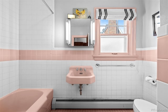 full bathroom featuring tile walls, toilet, a baseboard radiator, a sink, and a bath