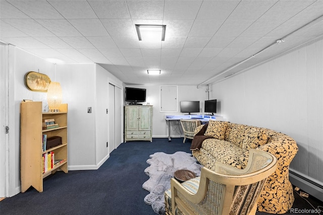 living area with a baseboard heating unit, dark colored carpet, and baseboards