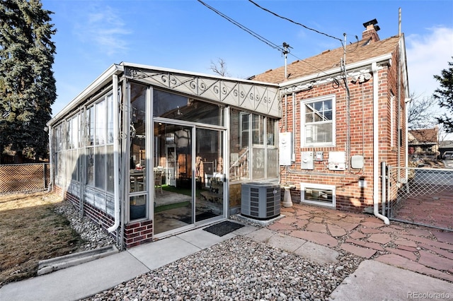 rear view of house featuring a patio, a sunroom, fence, central AC, and brick siding