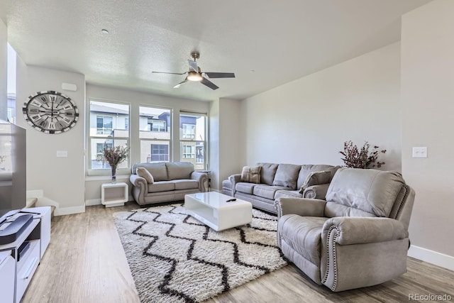 living room featuring ceiling fan, a textured ceiling, and light hardwood / wood-style flooring