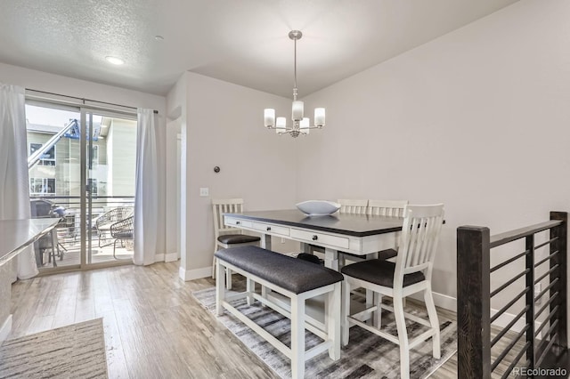 dining area featuring an inviting chandelier, light hardwood / wood-style floors, and a textured ceiling