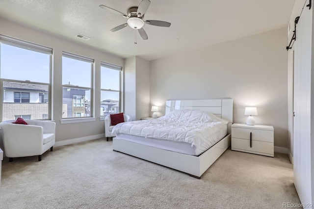 carpeted bedroom featuring ceiling fan and a barn door