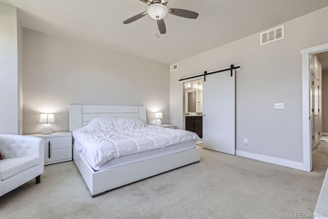 carpeted bedroom with connected bathroom, ceiling fan, and a barn door