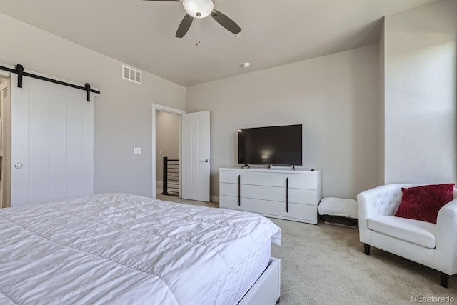 bedroom featuring light colored carpet, ceiling fan, and a barn door