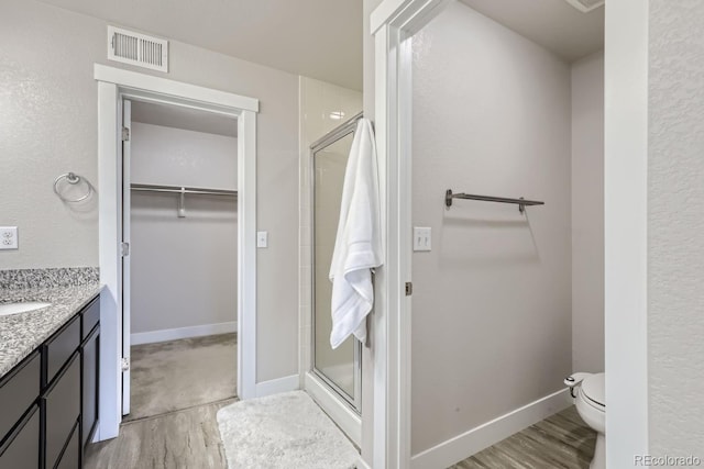 bathroom with hardwood / wood-style flooring, toilet, a shower with shower door, and vanity