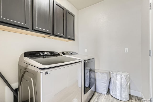 washroom with light hardwood / wood-style floors, cabinets, and washer and dryer