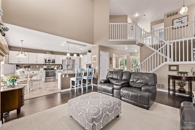 20710 E Princeton Pl, Aurora, CO 80013 - living area featuring stairs, dark wood-style flooring, a towering ceiling, and recessed lighting