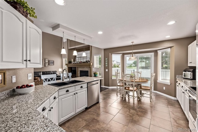 20710 E Princeton Pl, Aurora, CO 80013 - kitchen with stainless steel appliances, white cabinetry, recessed lighting, a peninsula, and a fireplace