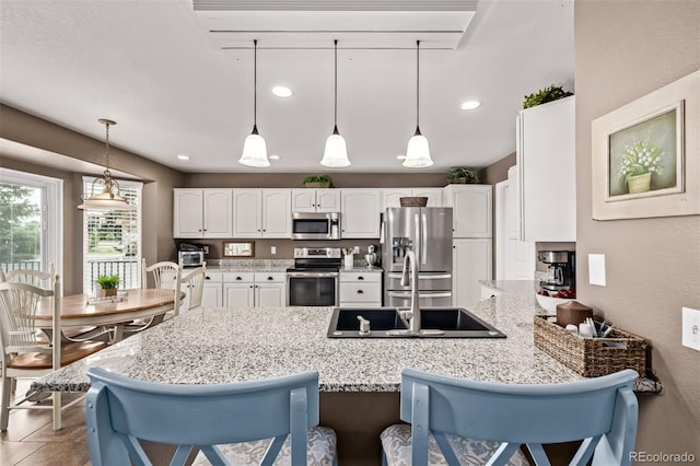 20710 E Princeton Pl, Aurora, CO 80013 - kitchen with stainless steel appliances, a peninsula, white cabinets, a kitchen breakfast bar, and light stone countertops