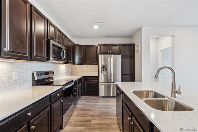 485 Interlocken Blvd Unit 201, Broomfield, CO 80021 - kitchen with appliances with stainless steel finishes, a sink, light stone counters, dark brown cabinets, and light wood-style floors