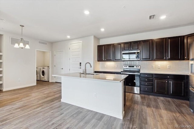 485 Interlocken Blvd Unit 201, Broomfield, CO 80021 - kitchen featuring appliances with stainless steel finishes, independent washer and dryer, a sink, light countertops, and a chandelier