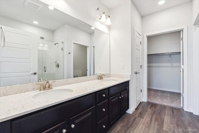 485 Interlocken Blvd Unit 201, Broomfield, CO 80021 - bathroom with a shower stall, double vanity, a walk in closet, wood finished floors, and recessed lighting