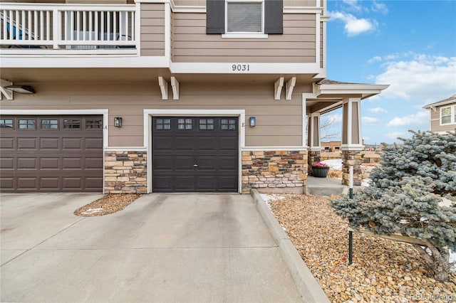 entrance to property featuring stone siding, concrete driveway, and an attached garage