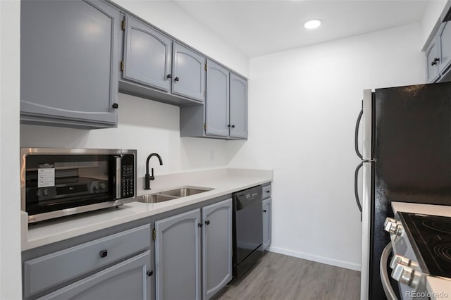 kitchen with light wood-type flooring, black dishwasher, gray cabinetry, and sink