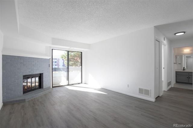 unfurnished living room with a textured ceiling, a brick fireplace, dark wood-type flooring, and sink