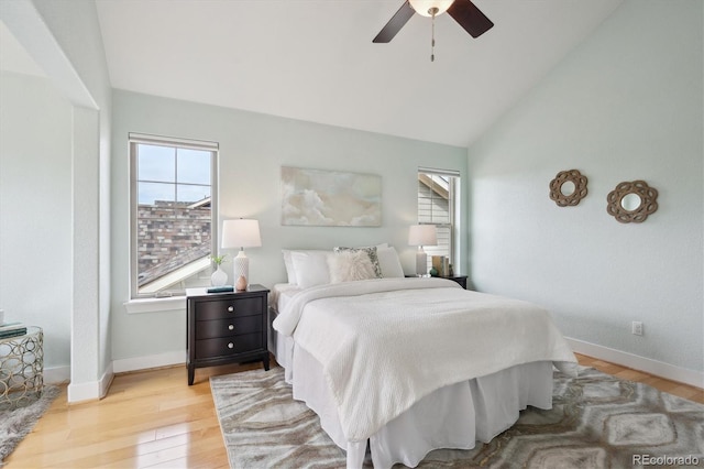 bedroom featuring baseboards, multiple windows, light wood-style flooring, and vaulted ceiling