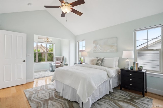 bedroom featuring baseboards, ceiling fan with notable chandelier, high vaulted ceiling, and wood finished floors