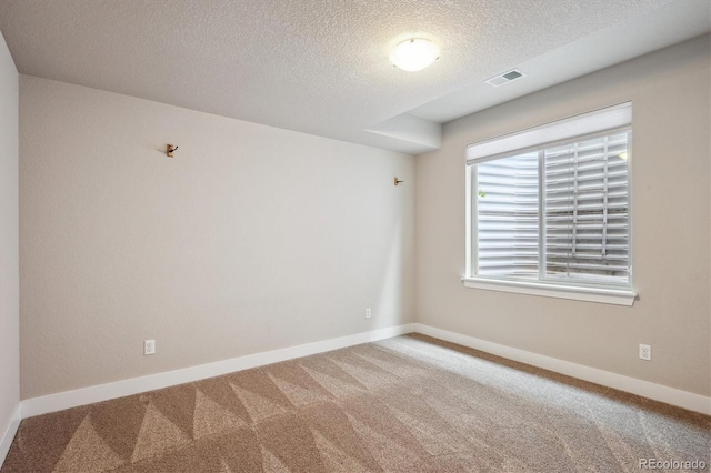 unfurnished room featuring a textured ceiling, carpet floors, baseboards, and visible vents