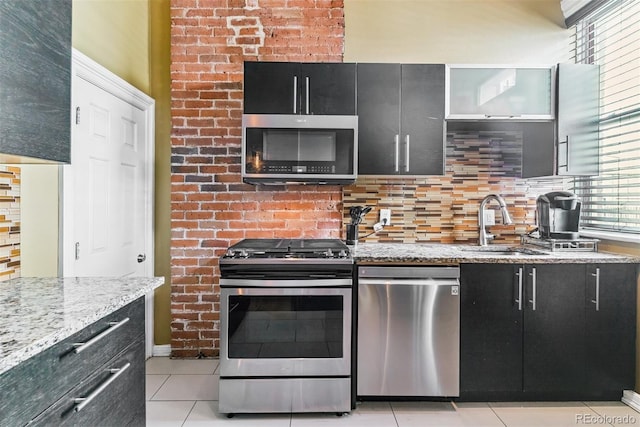 909 W Park Ave, Denver, CO 80205 - kitchen featuring stainless steel appliances, dark cabinetry, light tile patterned floors, decorative backsplash, and light stone counters