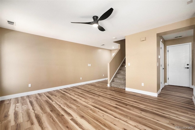 unfurnished living room with visible vents, stairs, baseboards, ceiling fan, and light wood-type flooring
