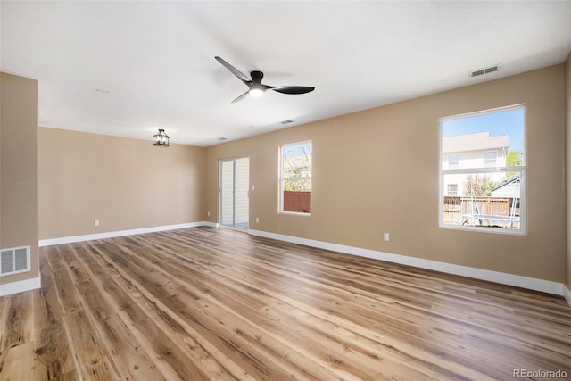 empty room with a ceiling fan, light wood-type flooring, and visible vents