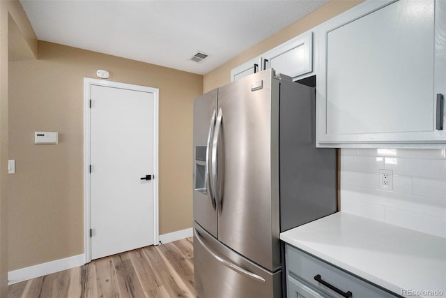 kitchen featuring light countertops, stainless steel fridge with ice dispenser, baseboards, and light wood finished floors