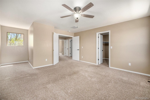 unfurnished bedroom featuring visible vents, light carpet, baseboards, a walk in closet, and a ceiling fan
