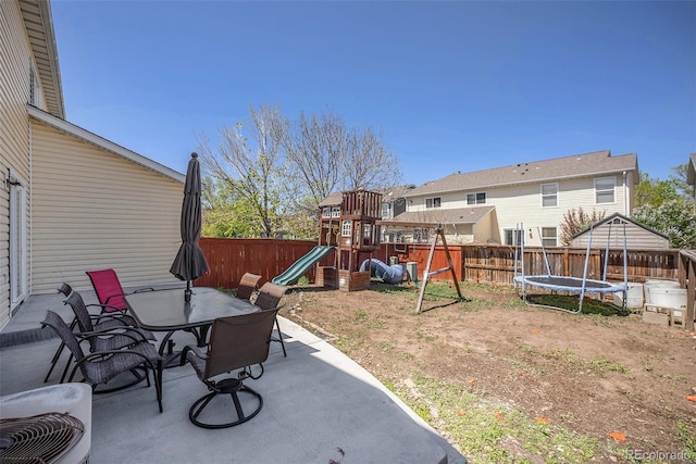 view of patio / terrace featuring a playground, a trampoline, a fenced backyard, and outdoor dining space