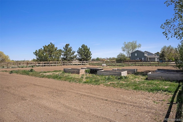 view of yard with a garden, fence, and a rural view